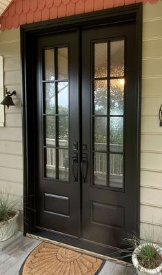 a black double door with two sidelights and a mat on the front porch area