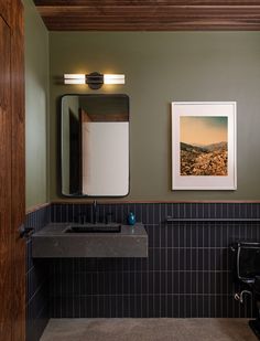 a bathroom with a sink, mirror and pictures hanging on the wall in front of it