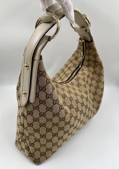 A stunning vintage Gucci hobo bag made from the iconic beige GG canvas with cream leather trim and pale gold hardware. Inside the bag is lined with a brown cotton lining and there is a zipped pocket for valuables. This bag is in excellent vintage condition, a true collectors item and comes with its original Gucci dust bag. There is some slight wear seen on the base corners. Pashanim Style, Gucci Hobo Bag, Fine Outfits, Living Single, Gucci Horsebit, Dream Bags, Vintage Bag, Pale Gold, Diaper Backpack