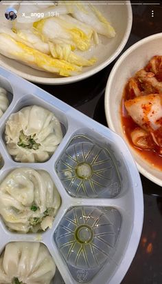 there are many different types of food in the trays on the table, including dumplings and vegetables