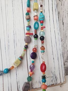 "Three stunning graduated strands of multi color, semi precious stones make up this long bold necklace. Just about every stone you can imagine; turquoise, garnet, lapis, pearl, chrysoprase, red coral, and carnelian, just to name a few. The stones are accented with Bali sterling silver fancy spacers. The longest strand measures 33\", the middle strand measures 30\" and the shortest strand measures 27\". All three strands are connected with a sterling silver lobster clasp. It is hand strung on a 4 Colorful Bohemian Jewelry With Gemstone Beads, Multicolor Natural Stones Hippie Jewelry, Hippie Multicolor Jewelry With Natural Stones, Hippie Multicolor Natural Stones Jewelry, Hippie Style Multicolor Natural Stones Jewelry, Bohemian Multicolor Round Beads Long Necklace, Bohemian Long Beaded Necklaces With Stones, Bohemian Multicolor Beaded Long Necklace, Bohemian Long Beaded Stone Necklace