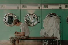 a boy is sitting on a bench in front of washers