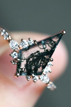 a close up of a person's hand holding a ring with diamonds on it