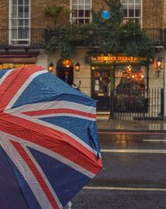 an open umbrella with the british flag on it is in front of a storefront