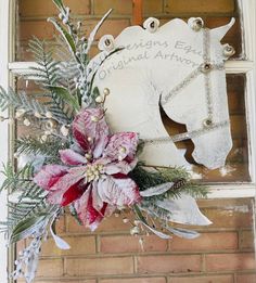 a white horse head mounted to the side of a brick wall with flowers and greenery