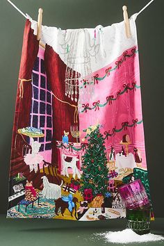 a tea towel hanging on a clothes line with a christmas tree in front of it