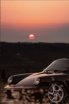 a black sports car parked in front of the sun