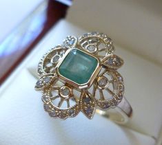 BEAUTIFUL ART NOUVEAU 9CT/9K SOLID GOLD VINTAGE INSPIRED EMERALD & DIAMOND FLOWER RING This lovely Vintage Inspired Art Nouveau ring has been crafted from 9ct Solid Gold. An  Emerald Cut Natural Emerald Gemstone lies in the centre surrounded by thirty two Genuine Diamonds including inset diamond petals forming a flower. A highlight of this ring is the milgrain edges and spoke pattern making this ring more appealing to the onlooker and wearer alike. THIS VINTAGE INSPIRED EMERALD/DIAMOND FLOWER RI Garnet Ring Vintage, Bijoux Art Nouveau, Art Nouveau Ring, Emerald Ring Vintage, Antique Style Rings, Gold Flower Ring, Vintage Inspired Art, Emerald Diamond Ring, Art Nouveau Jewelry