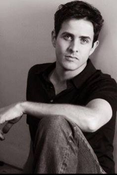 a black and white photo of a man sitting on the floor with his arms crossed