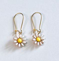 "Gold flower earrings, drop dangle earrings with daisy white flower yellow center, daisy earrings daisies, Boho hippie vibes, pretty feminine floral spring summer aesthetic jewelry *earring wires measure just under approx 1\" *charm itself approx half an inch *materials - gold tone alloy earring wires & charms with enamel *back of charms are plain gold color *comes in a gift box" Spring White Earrings With Ear Wire, White Earrings With Ear Wire For Spring, White Single Earring For Spring, Dainty White Dangle Flower Earrings, White Daisy-shaped Hypoallergenic Flower Earrings, White Flower Charm Earrings For Everyday, Dainty White Earrings For Spring, Adjustable White Flower Earrings For Spring, White Dangle Flower Earrings For Spring