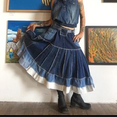 a woman wearing a denim skirt and cropped top standing in front of paintings on the wall