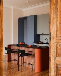 a kitchen with an island and chairs in the center, next to a wooden door