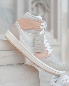 a pair of white and pink sneakers on top of some steps in front of a building