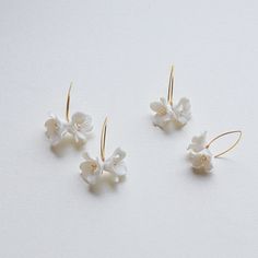 Each earring is exquisitely made by hand, featuring two delicate white clay flowers adorned with freshwater pearls. Skillfully handcrafted, these flower bridal earrings are the perfect complement to our signature porcelain headpieces.  These earrings are extremely lightweight. They are very elegant in their simplicity and have a very versatile design that would match many different wedding dress styles. ITEM SPECIFICATIONS ♥Flower Size about : 0.4*0.4in  0.6*0.6in ♥The earrings are available in Adjustable White Jewelry With Flower Decoration, Elegant White Flower Hoop Earrings, White Wedding Jewelry With Flower Decoration, White Flower Decoration Wedding Jewelry, Handmade White Flower Hoop Earrings, Delicate Handmade White Hoop Earrings, Delicate White Hoop Earrings For Wedding, Delicate White Handmade Flower Earrings, White Flower Earrings For Celebration