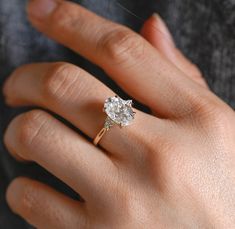 a woman's hand with a diamond ring on top of her finger and an engagement band