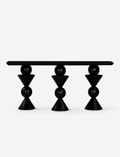 three black balls on top of each other near a table with an oval glass top