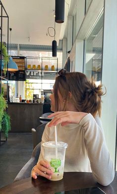 a woman sitting at a table with a drink in her hand