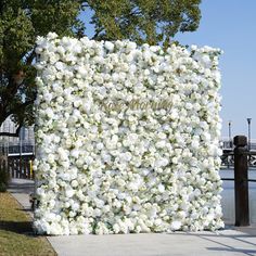 a large white flowered wall on the side of a road next to a body of water