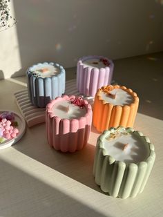 five different colored candles sitting next to each other on top of a white countertop