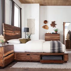 a bed sitting in a bedroom next to a dresser with drawers on each side and a mirror above it