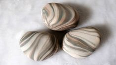 three marbled rocks sitting on top of a white surface