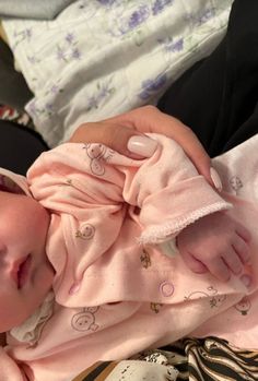 a baby laying on top of a bed covered in pink blanket next to a pillow