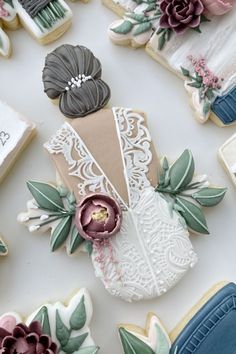 decorated cookies with flowers and laces on top of a white tablecloth covered in frosting