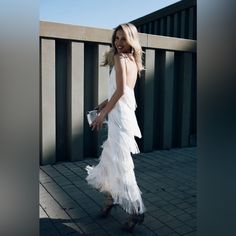 a woman in a white dress is walking down the street with her hand on her hip