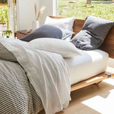 a bed with pillows and blankets on it in a room next to a large window