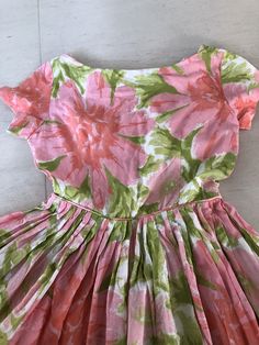 "This lovely sundress is all sweetness and sunshine. Pinks and greens are such a great combination! I loveeeee the pink mother of pearl buttons! Bust 36\" Waist 26\" Length 38\" This item is clean and ready to wear. Comes from a smoke and pet free home. Don't forget to follow me on Instagram @tammaraclearshercloset for new listing alerts. This is shipping from Singapore. Standard post takes about 10 working days. Please contact me if you need it urgently. H151" Pink Tea Length Summer Dress, Pink Tea-length Summer Dress, Summer Garden Party Dress With Box Pleat, Spring Tea-length Dress With Box Pleat, Summer Dresses With Box Pleat And Full Skirt, Pink Fitted Dress With Box Pleat, Mid-century Floral Print Dress For Spring, Vintage Pink A-line Dress, Spring Dresses With Box Pleat