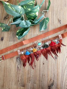 Elevate your bohemian style with our exquisite handcrafted boho belt. This unique accessory features a rich brown leather strap adorned with an intricate band of decorative elements. The centerpiece of the belt is a vibrant and detailed design that includes colorful tassels in shades of red, blue, orange, and green, as well as delicate metallic charms and coins that add a touch of sparkle and movement. Adding to its eclectic charm, the belt is further embellished with a row of soft, reddish-brow Feather Belt, Colorful Tassels, Boho Belt, Boho Mode, Boho Belts, Detailed Design, Orange And Green, Brown Leather Strap, Decorative Elements