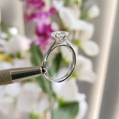 a close up of a diamond ring with a flower in the back ground behind it