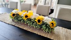 sunflowers and greenery are arranged in a rectangular arrangement on the dining room table