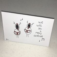 a christmas card with two reindeers and musical notes on the front one has a note that says, wish you a merry christmas