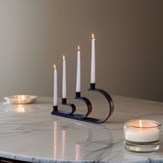 candles are lit on a marble table with a candle holder in the shape of a spiral