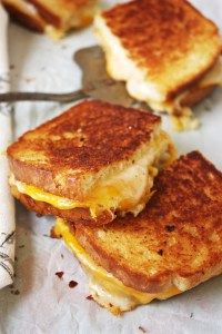 two grilled cheese sandwiches sitting on top of a piece of paper