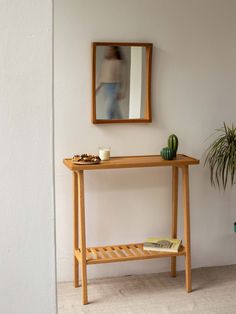 a wooden table sitting next to a mirror and potted plant on top of it