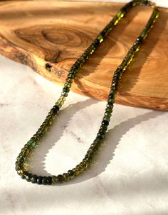 "Details: Gemstone: Natural Highest Quality Green Tourmaline, 5mm, faceted rondelle Closure: 14k solid yellow gold clasp, 6mm Jump ring: 14k solid yellow gold jump ring, 6mm Bead tip: 14k solid yellow gold, 3mm Bead: 14k solid yellow gold, 3mm, rondelle The necklace length is 17\". This beautiful necklace goes with everything. One of a kind necklace. Green Tourmaline: Green Tourmaline attracts luck, success, abundance and prosperity. It inspires creativity, and may be used to project, create and manifest one's goals." Tourmaline Gemstone Beads Necklaces, Faceted Rondelle Yellow Gold Necklaces, Tourmaline Single Strand Necklace With Round Beads, Yellow Gold Faceted Rondelle Necklaces, Yellow Gold Faceted Rondelle Necklace, Faceted Tourmaline Round Beads Jewelry, Bead Tips, Yellow Gold Necklace, Natural High