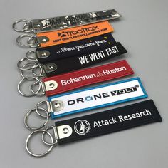 six keychains with different logos on them, each one has a name tag