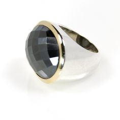 a ring with a large black stone on it's center and two tone gold accents