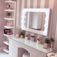 a white vanity with lighted mirror and stool in a pink room next to striped wallpaper