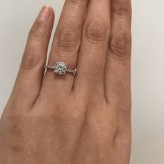 a woman's hand with a diamond ring on top of her finger and the other hand holding an engagement ring