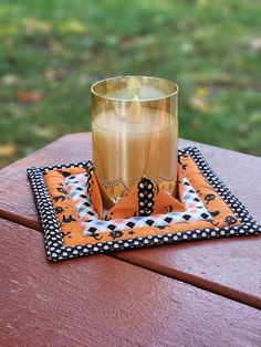 a glass sitting on top of a wooden table next to a plate with a candle