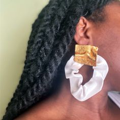 a woman wearing large gold and white earrings