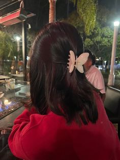 a woman sitting at a table with a butterfly in her hair