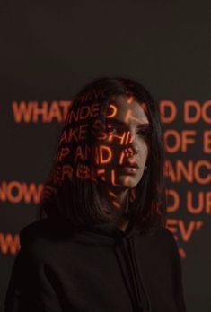 a woman standing in front of a wall with words on it and the word what do you