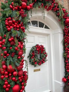 christmas wreaths and decorations on the front door of a house