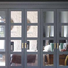 a living room filled with lots of furniture next to a wall covered in glass doors