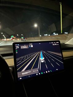 a laptop computer sitting on top of a car dashboard in a vehicle at night time