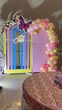 a table topped with balloons and a butterfly arch